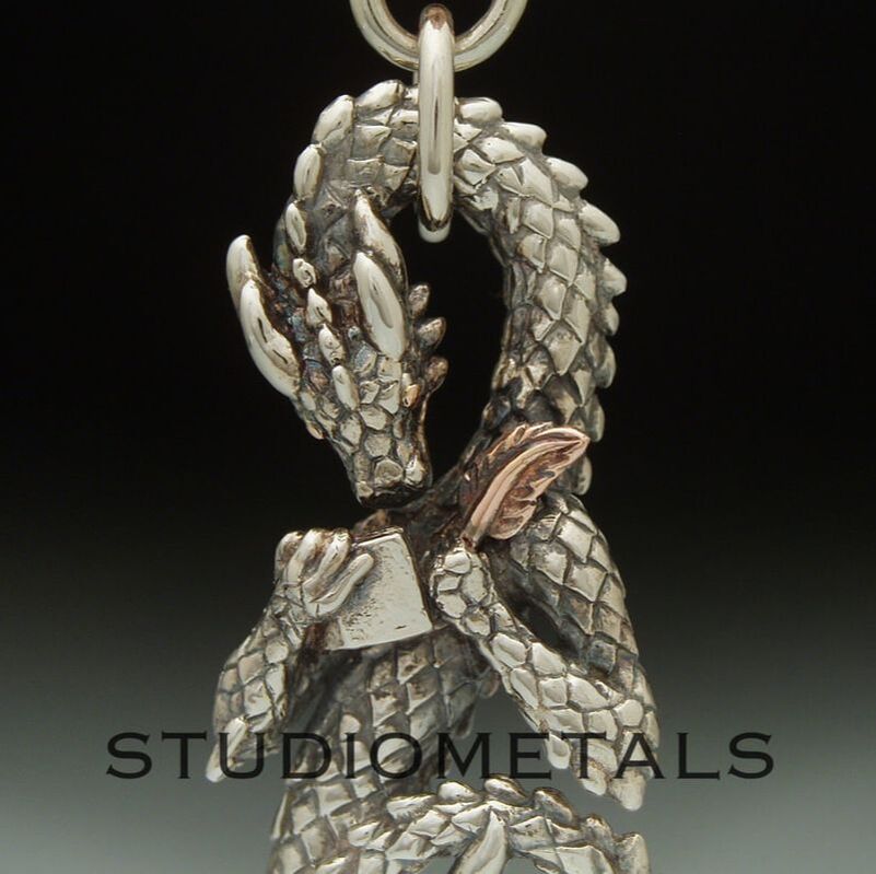 Hand carved western dragon pendant with Cetic knot work. Dragon writing in a diary with a rose gold quill.