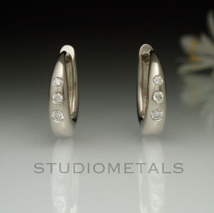 14k white gold, hinged, 13mm oval huggie hoop earrings with flush diamonds.