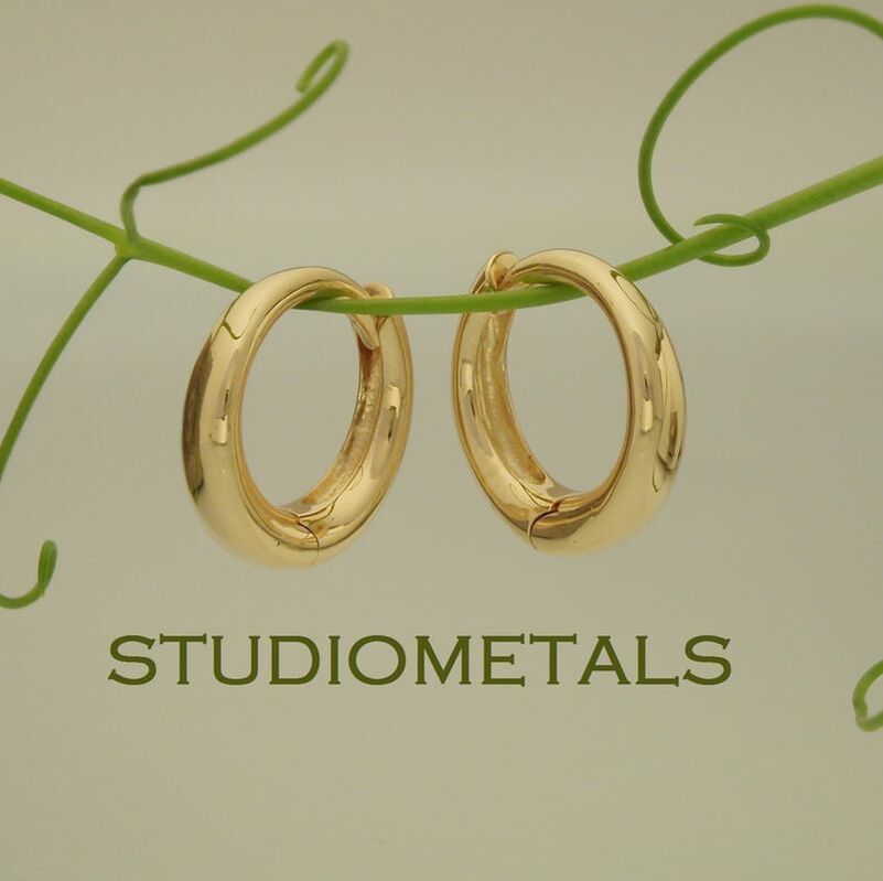 11mm oval, hinged huggie hoop earrings in solid 14k yellow gold.