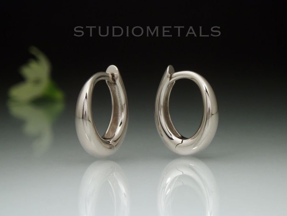 Nickel free, 14k palladium white gold, oval huggie hoops with hinges and a polished finish. 