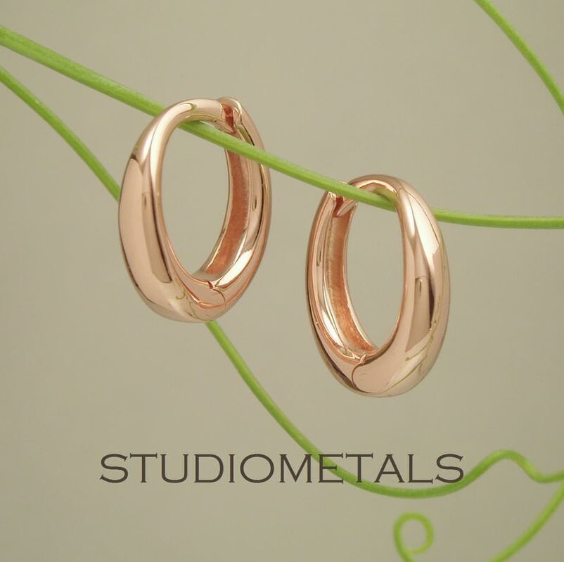 13mm oval hinged huggie hoops in solid 14k rose gold.