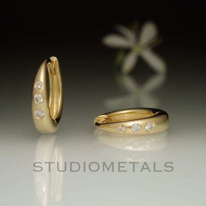 12mm round huggie hoop earrings in polished 14k yellow gold with flush set VS diamonds.