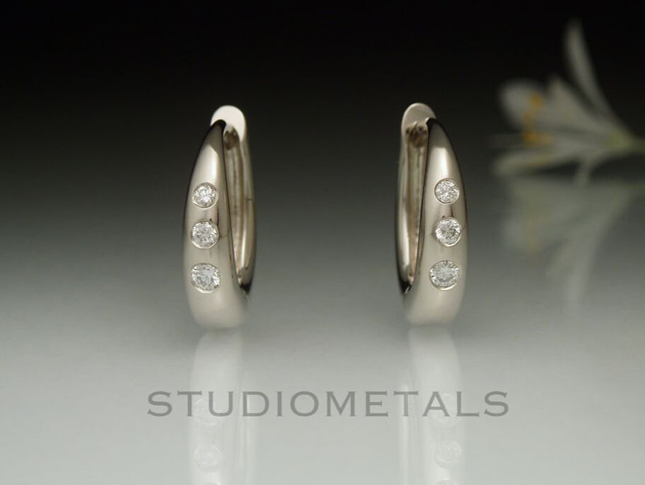 14k white gold, hinged, 13mm oval huggie hoop earrings with flush diamonds.