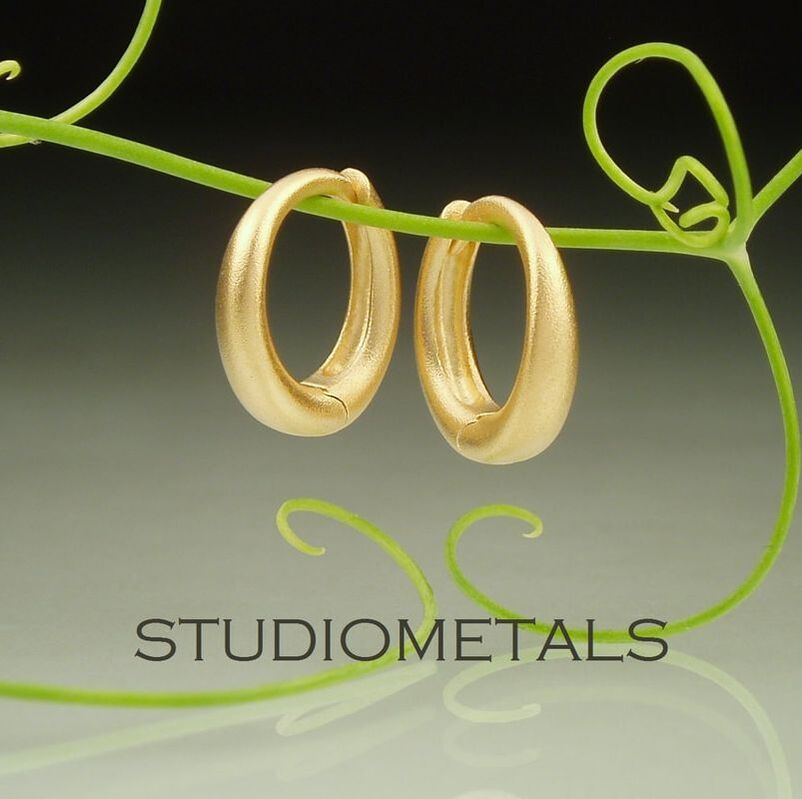 matte 18 karat yellow gold hinged huggie hoop earrings.