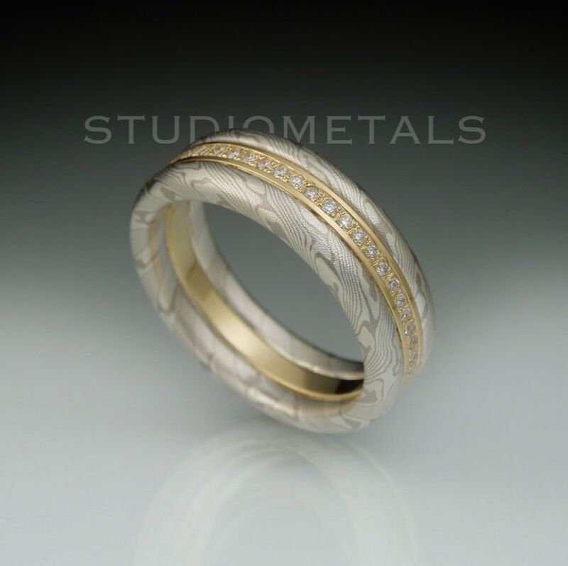 Creative moder womens wedding band in white mokume and 18 karat yellow gold with 25 pave set vs diamonds.