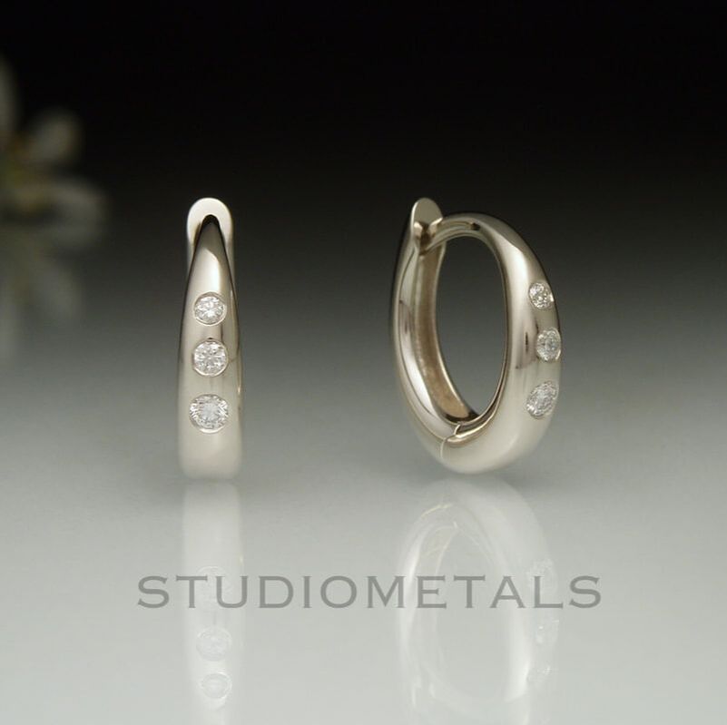 13mm oval huggie hoop earrings in polished 14k white gold with flush set, naural vs clarity diamonds.