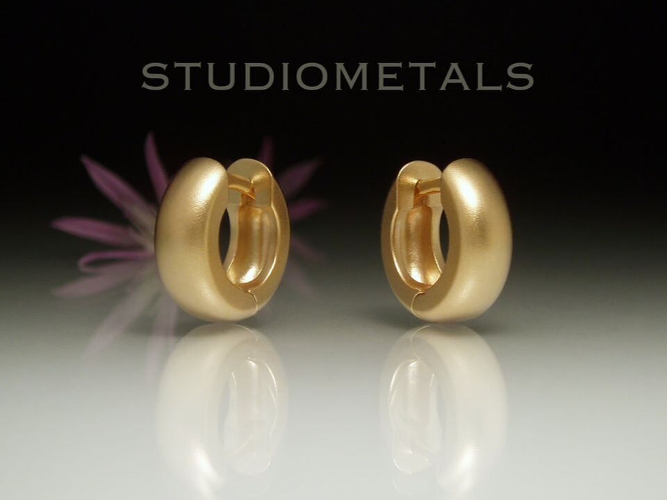 wide, hinged huggie hoop earrings in satin matte 14 karat yellow gold.